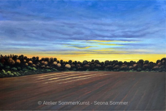 Landschaft mit Ackerfläche und farbenfrohem Himmel bei Sonnenuntergang.