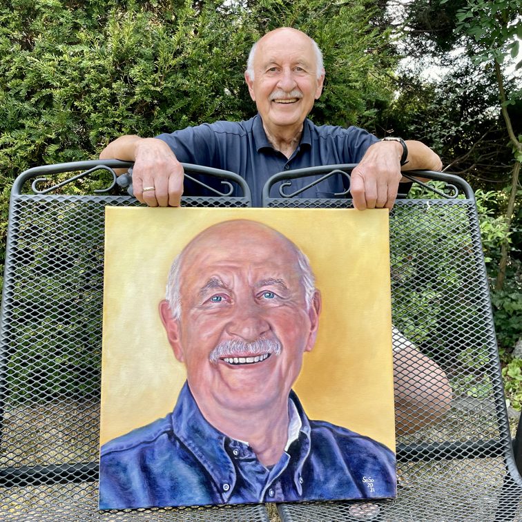 Älterer Mann zeigt stolz ein Ölporträt von sich selbst.