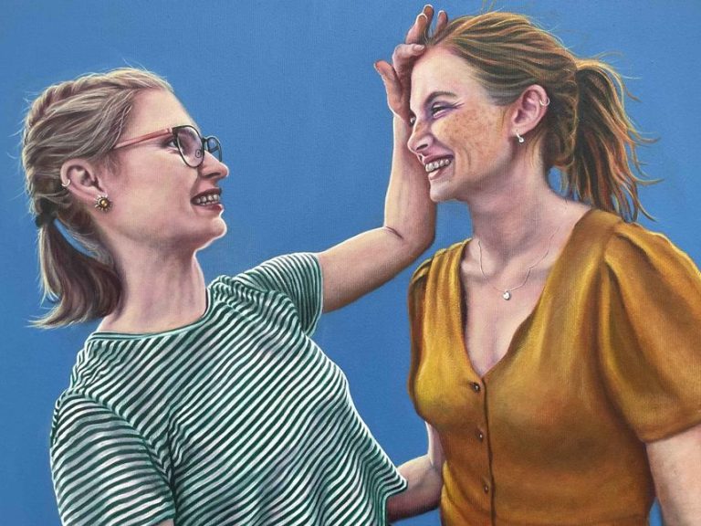 Ölporträt: Zwei Frauen lachen und interagieren fröhlich vor einem einfarbigen blauen Hintergrund.